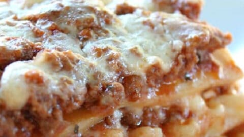 A slice of lasagna on a white plate.