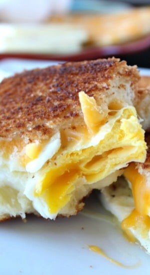 A close up of a fried egg sandwich with a couple bites taken out of it.