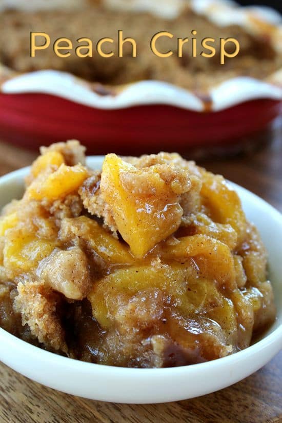 A white bowl with a serving of peach crisp in it.