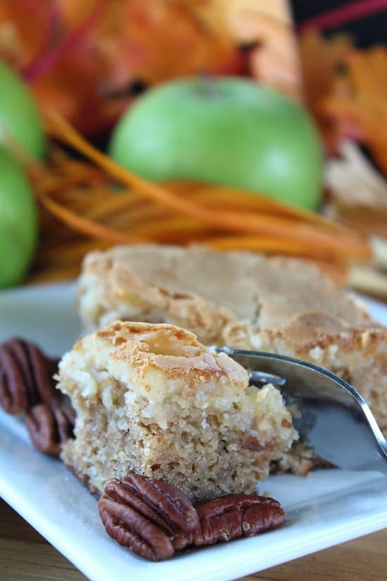 A piece of apple cake with a fork getting a bite on it.