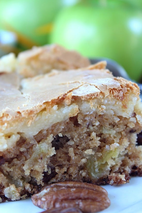 A close up of a piece of apple cake with a cheesecake layer on top.
