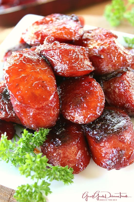 A close up photo of a white plate with a stack of bite-size BBQ smoked sausage bites on it.