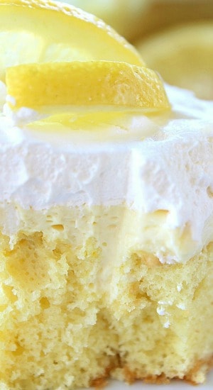 A close up of a slice of cream cheese lemonade poke cake with cool whip on top.