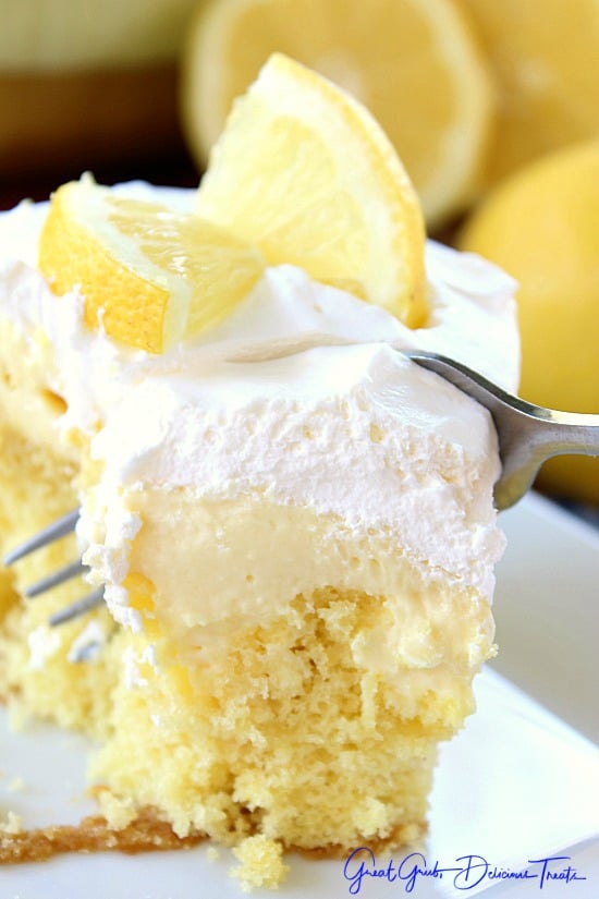 A close up of a fork going into a slice of lemon poke cake.