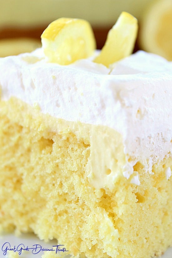 A slice of lemon poke cake showing the filling and the cool whip topping.