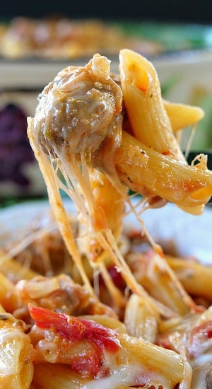 A fork filled with a bite of pasta with sausage.