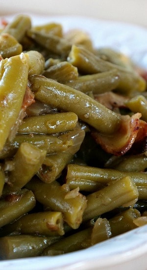 A close up of a serving of bacon green beans in a white bowl.
