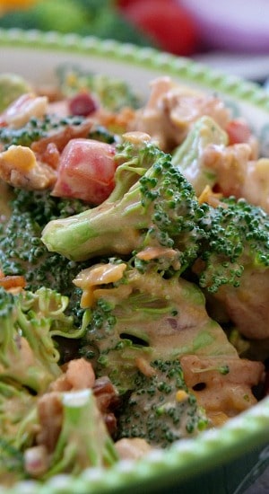 A green and white bowl with a serving of barbecue bacon broccoli salad in it.
