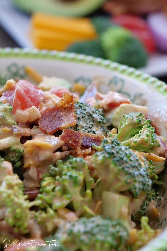 A green and white bowl with a serving of bacon broccoli salad in it.