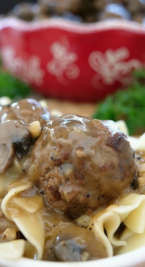 A close up picture of a Salisbury steak meatball sitting on a bed of egg noodles with mushroom gravy.