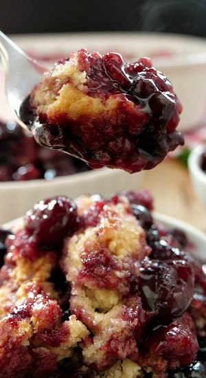 A close up of a spoonful of cherry cobbler.