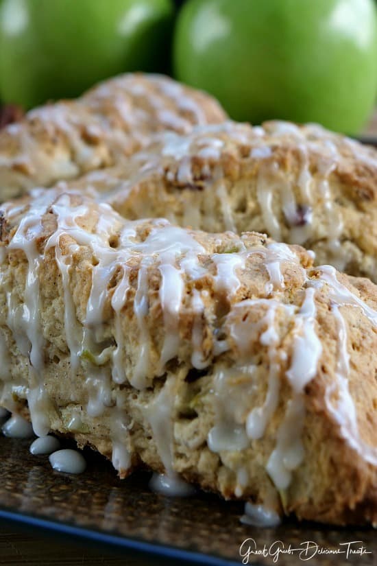 Apple Pecan Scones - 3 scones with glaze drizzled over the top with 2 green apples in the background.