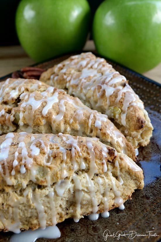 Apple Pecan Scones - 3 scones on a brown plate with two green apples in the background.
