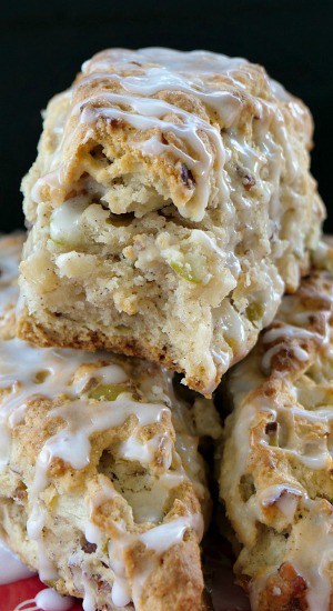 Close up of 3 apple pecan scones with one bite taken out of the scone sitting on top of the other two scones.