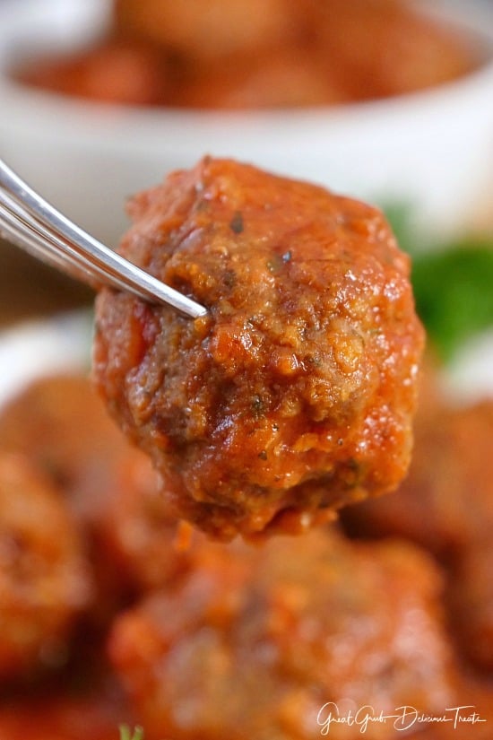 A single meatball on a fork held close to the camera lens.