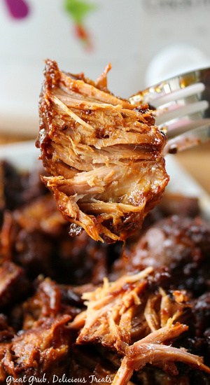 A fork with a bite of crock pot country style pork ribs on it.