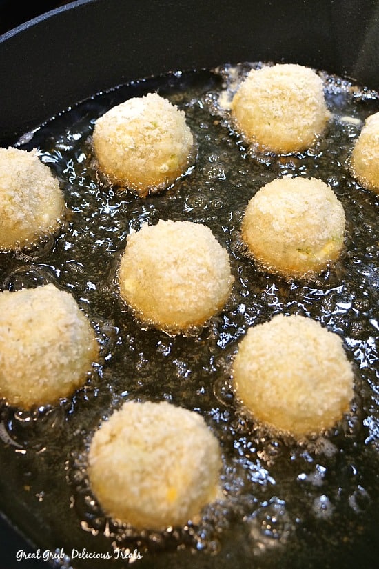 A frying pan filled with oil and frying bite-size cream cheese avocado bites.