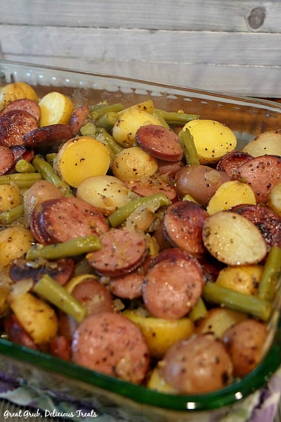 A glass baking dish filled with sausage green beans and potatoes.