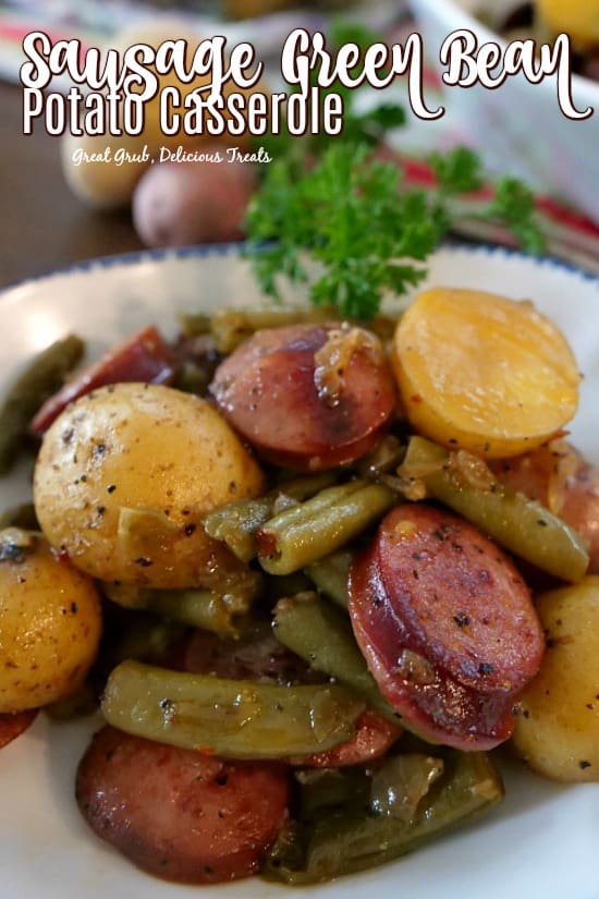 A close up of a white bowl with a serving of sausage green beans and potatoes.