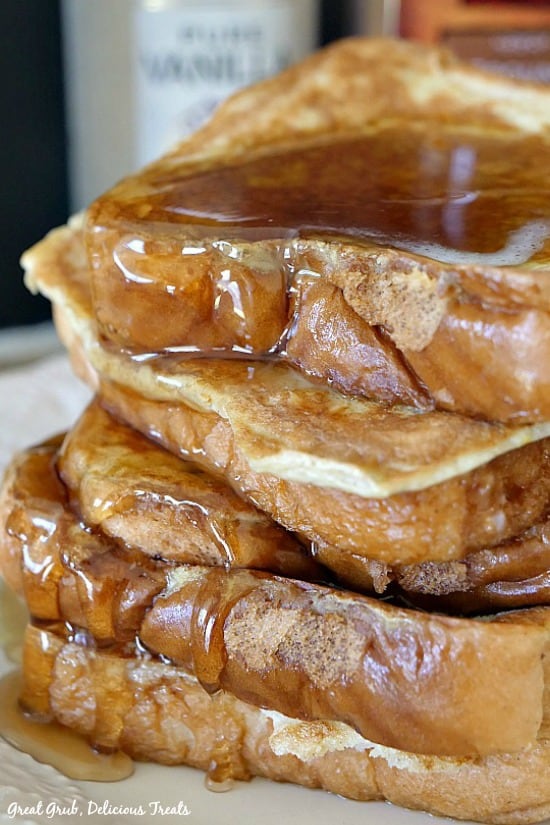 A stack of Texas Style French Toast with syrup dripping off the sides after being smothered in maple syrup.