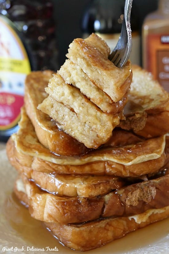 Texas Style French Toast is stacked up with 5 pieces and a fork holding 4 pieces and ready to be consumed.