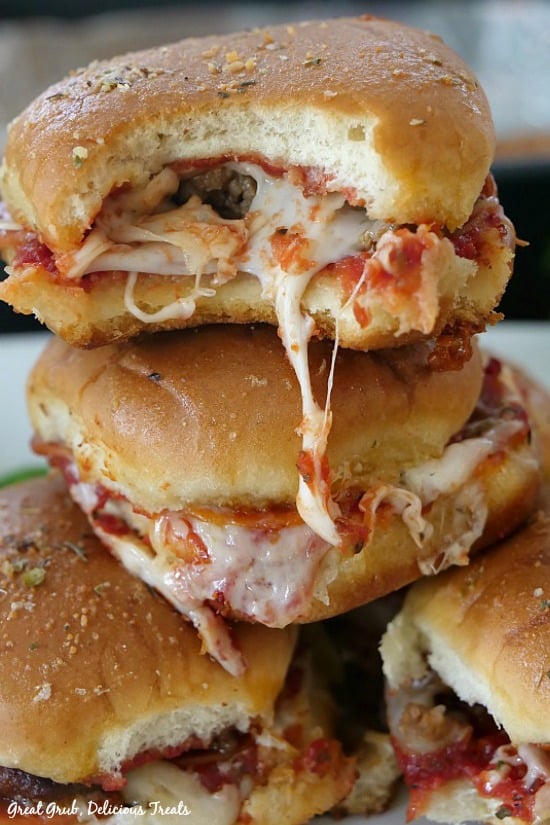 Pepperoni Sausage Pizza Sliders stacked on top of each other with a bite taken out and the melted cheese oozing.