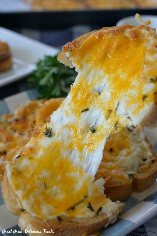 Garlic Cheese Bread is a piece of cheesy bread being pulled in half with the cheese stretching.