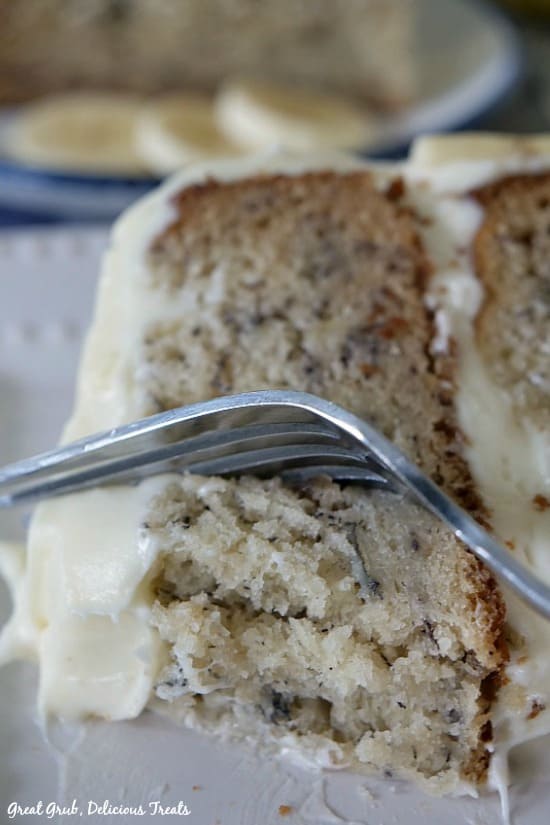 Banana Cake with Cream Cheese Frosting is a piece laying on it's side with a fork getting a bite on it.
