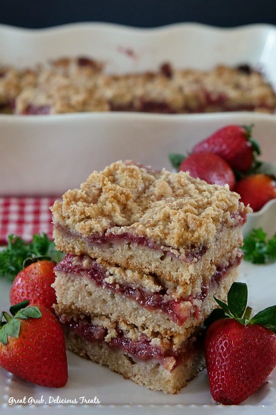 Strawberry Crumb Bars stacked three high with strawberries on the sides.