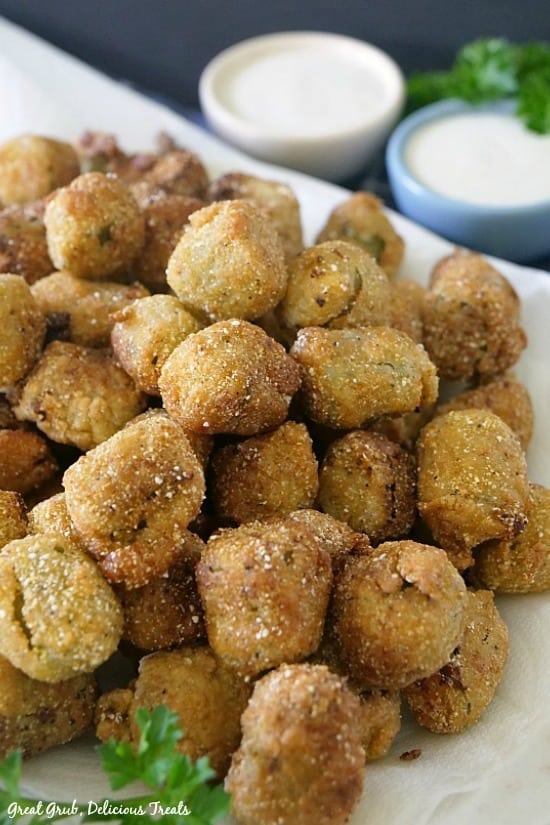 Spicy Fried Okra Nuggets on a plate with two dipping sauces in a white bowl and blue bowl.