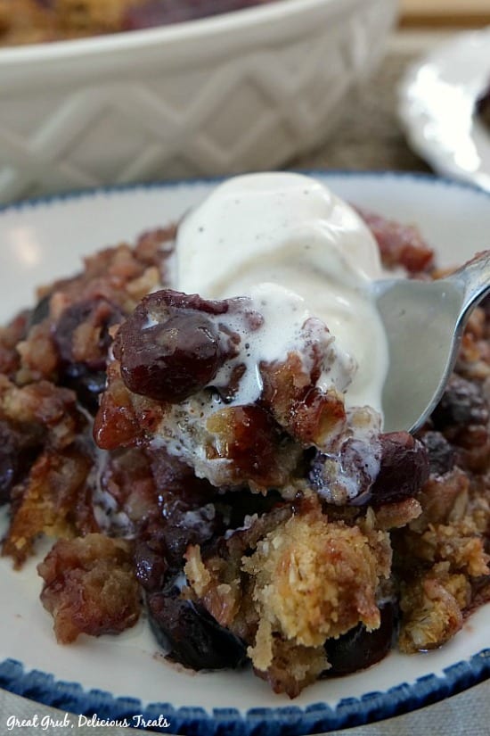 Easy Cherry Crisp shows a bowl filled with cherry crisp with a scoop of ice cream on top and a spoon digging into the crisp.