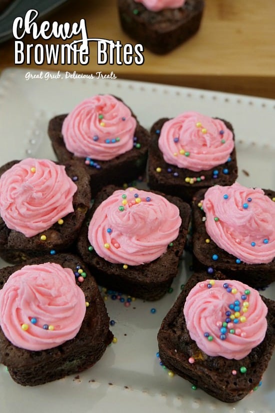 Chewy Brownie Bites - 7 bite size chocolate brownies with pink frosting sitting on a white plate.