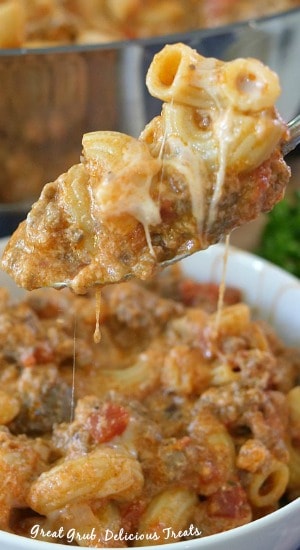 A close up of a spoonful of pasta, ground beef, and cheese. 