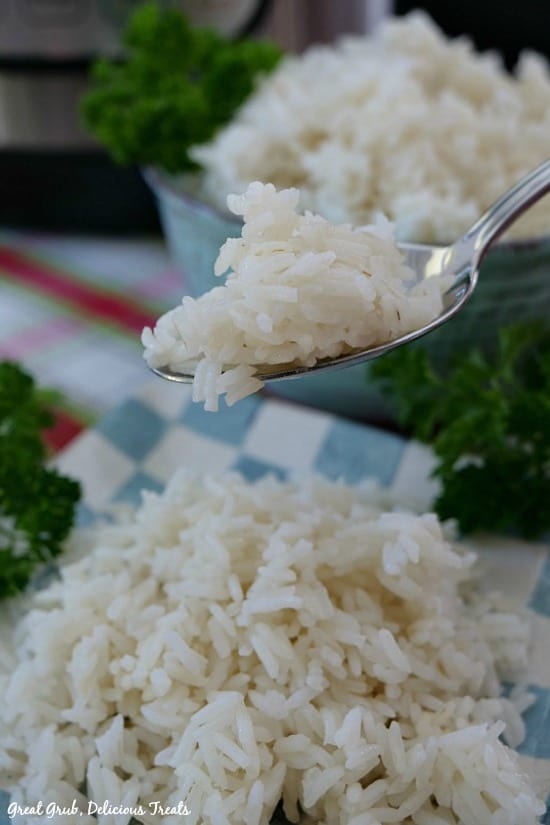 Instant Pot White Rice - a picture of a spoonful of rice with the plate of rice below and a bowl full of rice in the background.