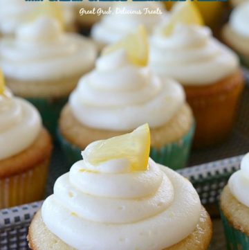 A close of photo of lemon cupcakes in a tray with small lemon wedges on top.
