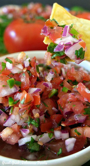 A close up of a tortilla chip that was dipped in the bowl of Pico de Gallo.
