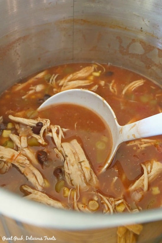 Best Chicken Tortilla Soup in a silver pot with a white ladle scooping out some chicken soup.