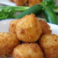 Mashed Potato balls on a white plate with jalapeños in the background