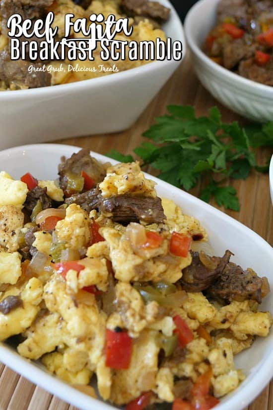 A white bowl filled with beef fajita breakfast scramble with two additional white bowls filled with the breakfast scramble.