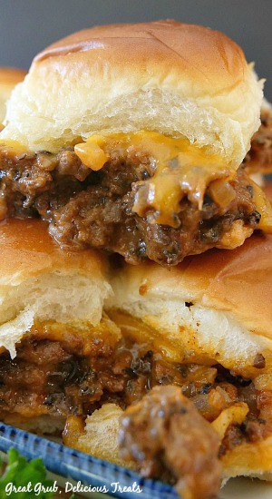 Three cheesy beef sliders stacked on top of one another, loaded with a ground beef mixture and cheese in between Hawaiian rolls then baked.