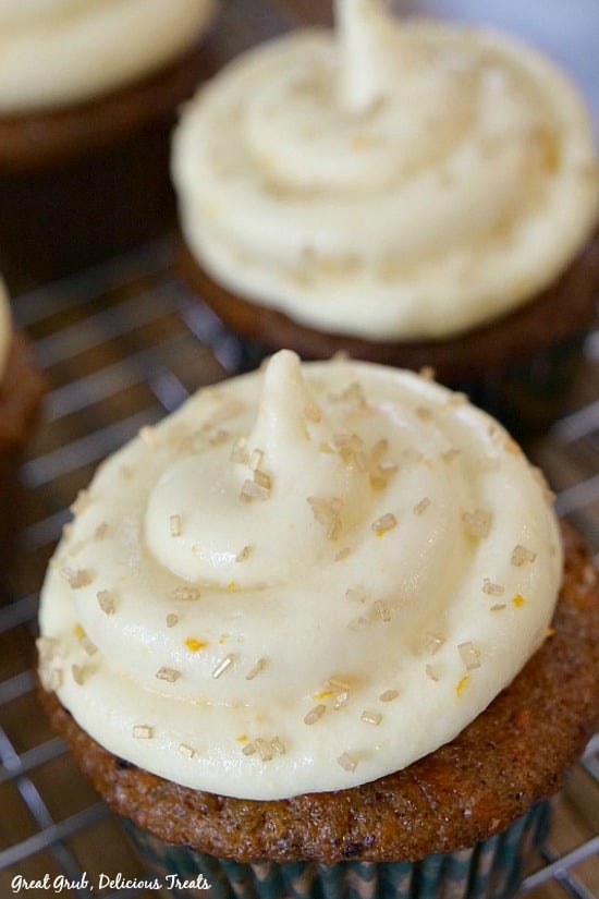 a close up picture of Carrot Cake Cupcakes with Orange Buttercream Frosting with more cupcakes in the background.
