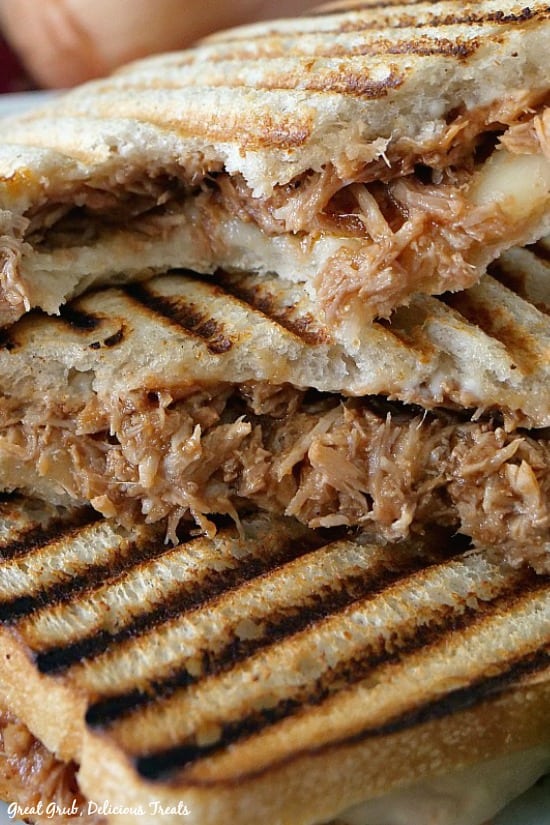 Close up photo of 3 halves of BBQ pulled pork panini sandwiches stacked on top of one another.
