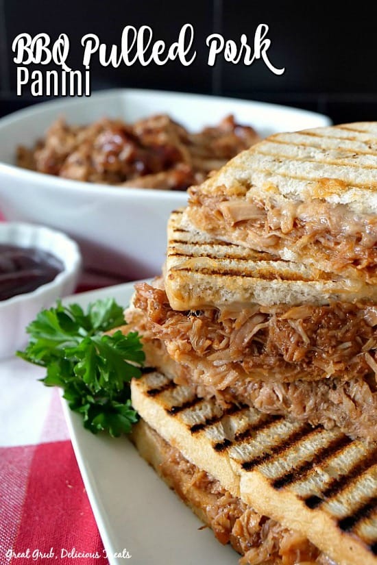 BBQ panini sandwich on a white plate with a white bowl of pulled pork in the background.