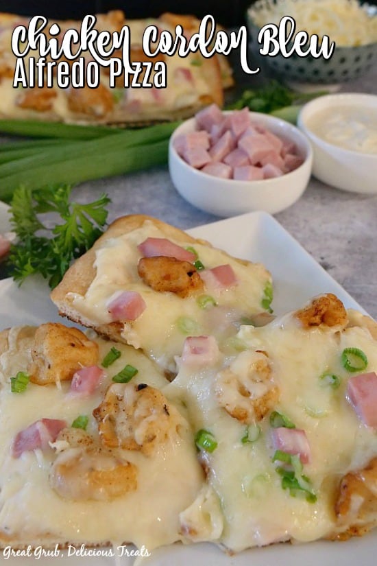Chicken Cordon Bleu Pizza - picture of a white plate with 3 square pieces of pizza with a white bowl of diced ham and one with alfredo sauce, one with shredded cheese and more pizza slices in the background.