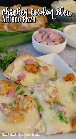 Chicken Cordon Bleu Alfredo Pizza - 3 pieces of pizza, on a white plate, that display crispy chunks of breaded chicken, diced ham, green onions and cheese with pizza, shredded cheese, diced ham and Alfredo sauce in the background.