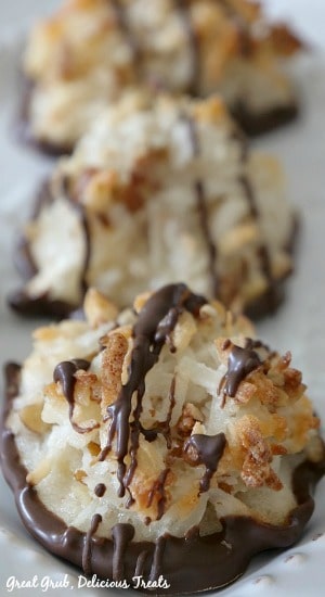 Close up photo of coconut pecan macaroon drizzled in chocolate on a cookie sheet.