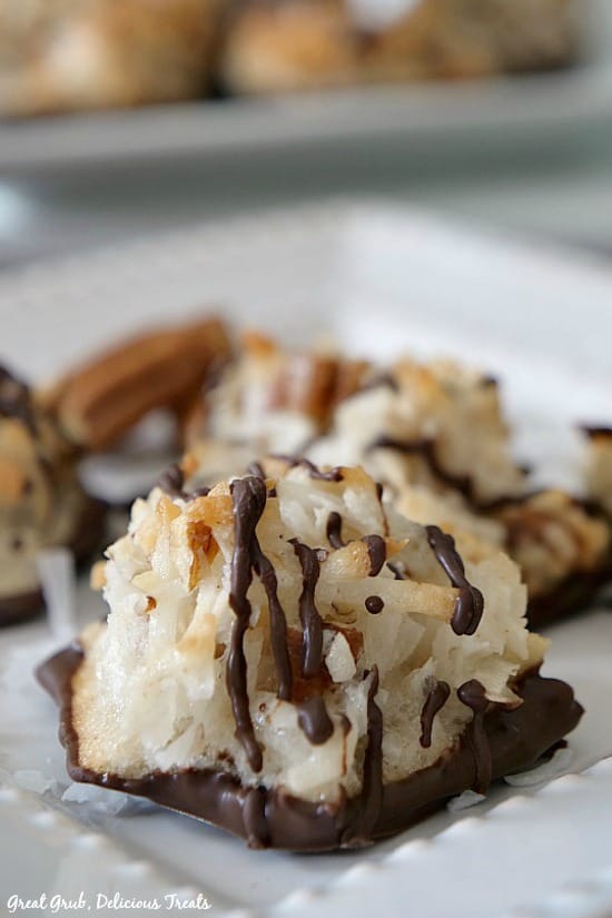 A single coconut pecan macaroon on a white plate with pecan pieces in the background.