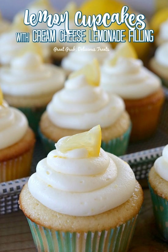 A close of photo of lemon cupcakes in a tray with small lemon wedges on top.