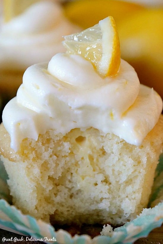 Delicious Lemon Cupcake with a bite taken out, showcasing the sweet lemonade cream cheese filling, topped with a lemon cream cheese frosting and a small lemon wedge.