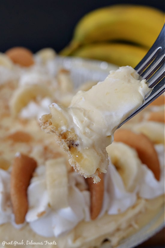 Easy Banana Pie - in this photo is a bite of banana pie on a fork showing the creamy pudding and a slice of banana with the whole pie and two bananas in the background.